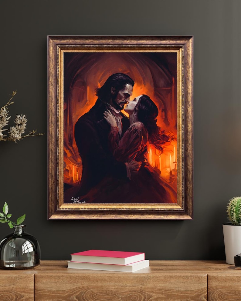 Puede incluir: Una obra de arte enmarcada representa una escena rom&aacute;ntica de una pareja abraz&aacute;ndose en un ambiente c&aacute;lido y ardiente. El hombre lleva un abrigo oscuro, mientras que la mujer viste un vestido rojo. El marco es dorado. La obra est&aacute; firmada.