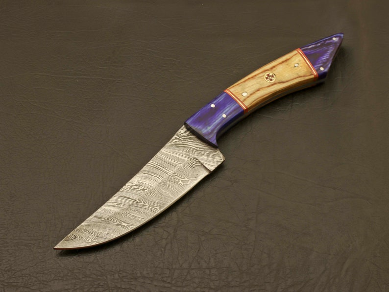 May include: A Damascus steel hunting knife with a blue and wood handle. The blade has a wavy pattern and the handle has a red accent.