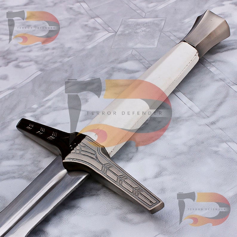 May include: A silver and white sword with a decorative handle and a black and silver cross guard. The sword has a white grip and a silver pommel. The blade is silver and has a black edge. The sword is on a white marble surface. "Terror Defender" is printed on the surface.
