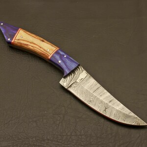 May include: A handcrafted knife with a blue and wood handle and a Damascus steel blade.