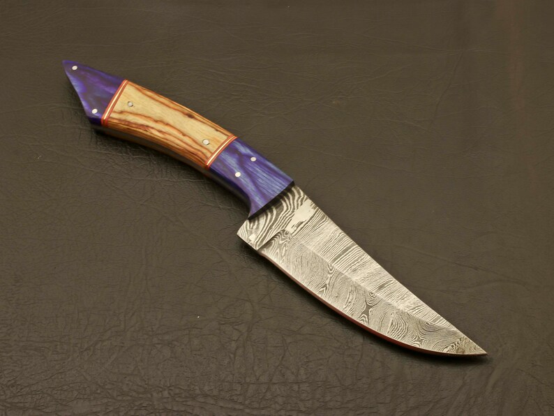 May include: A handcrafted knife with a blue and wood handle and a Damascus steel blade.