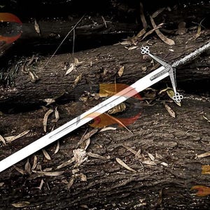 May include: A silver sword with a detailed hilt and a long, sharp blade. The sword is lying on a bed of brown tree branches and leaves.