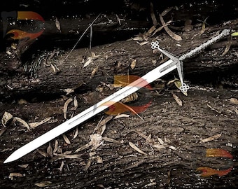 May include: A silver sword with a detailed hilt and a long, sharp blade. The sword is lying on a bed of brown tree branches and leaves.