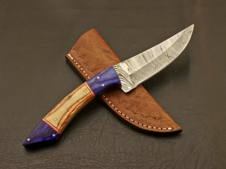 May include: A blue and brown handled knife with a Damascus steel blade, in a brown leather sheath.