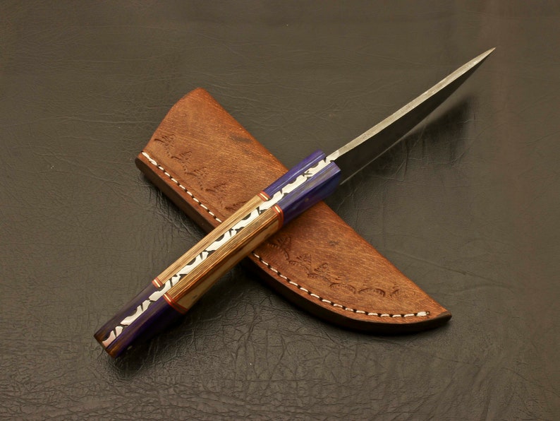 May include: A handmade knife with a blue and wood handle and a leather sheath. The blade is made of Damascus steel.