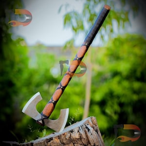 May include: A handcrafted axe with a double-sided blade. The wooden handle is wrapped in brown leather with black leather accents and brass rivets. The axe head is silver and the handle is angled against a tree stump.
