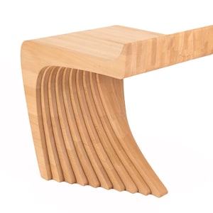 Puede incluir: Un taburete de madera con un diseño curvo en forma de ola. El taburete está hecho de madera clara y tiene un acabado liso y pulido.