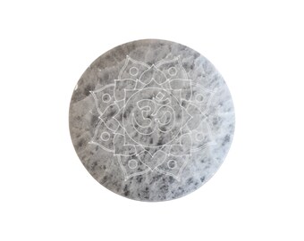 Peut inclure: Une pierre ronde grise avec un symbole Om blanc et un motif de mandala.