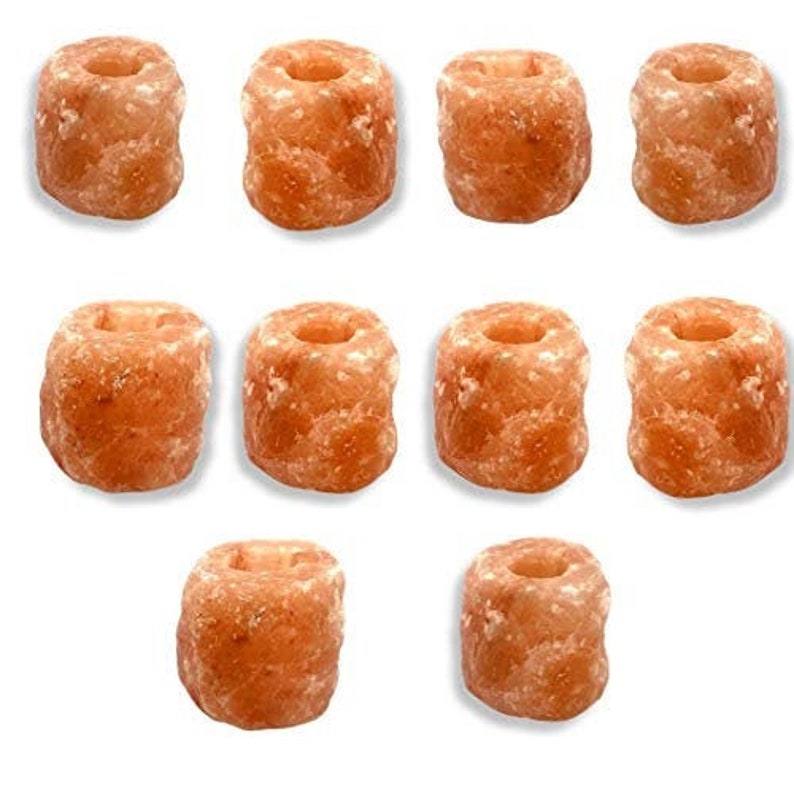 May include: Ten natural Himalayan salt candle holders in a light orange color. The candle holders are shaped like small cylinders with a hollow center for a tea light candle.