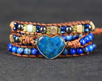 Puede incluir: Un brazalete de envoltura de varias capas con cordón de cuero azul y marrón, cuentas de lapislázuli azules y un gran dije de corazón de ágata azul.
