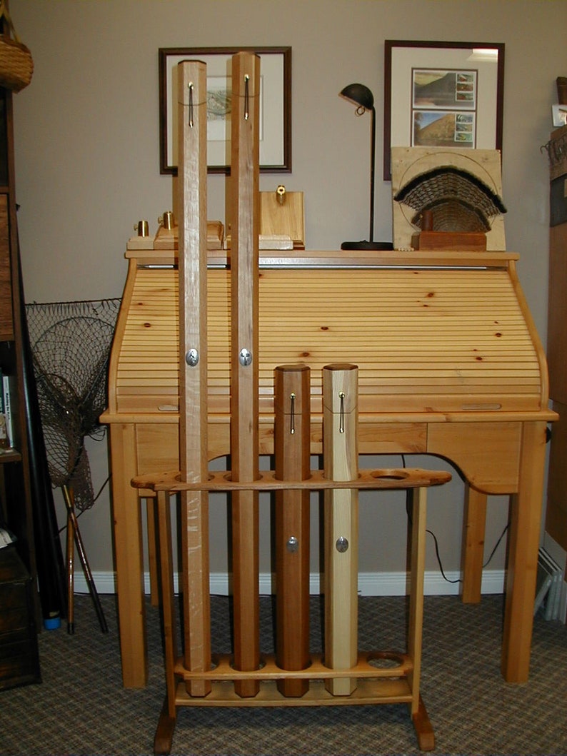 May include: A wooden rod holder with five wooden rods standing upright. The holder is made of light brown wood and has a dark brown stain. The rods are different lengths and have a natural wood finish.