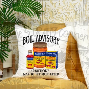 May include: White pillow with the text "BOIL ADVISORY" and images of crab boil seasoning jars. The text "*CAUTION* MAY BE PEE-MON-TAYED" is below the jars.