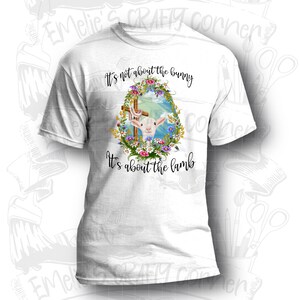 May include: White t-shirt with a graphic of a lamb in a wreath of flowers and a cross. The text "It's not about the bunny It's about the lamb" is printed on the shirt.