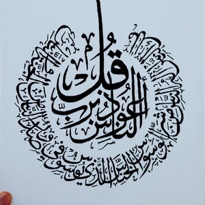 May include: Black and white calligraphy art print featuring a circular design with Arabic script. The script is in a decorative style and is centered on the page.