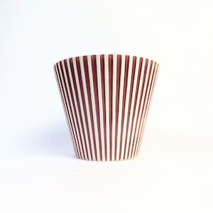 May include: A decorative, tapered ceramic vase with a white and burgundy striped pattern. The stripes run vertically from the base to the rim. The vase is set against a plain white background.