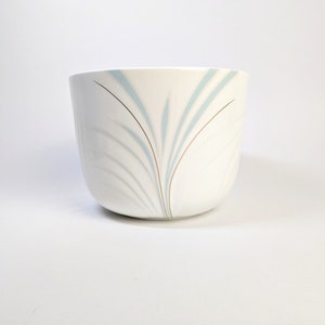 May include: White ceramic cup with a blue and gold abstract design.