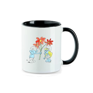 Könnte beinhalten: Weiße Keramiktasse mit schwarzem Rand und Henkel. Die Tasse zeigt eine Comic-Illustration von zwei Schlumpf, einer hält einen Strauß roter Blumen, mit dem Text "M3" in der linken unteren Ecke.