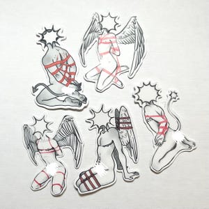 May include: A set of six stickers. Each sticker features a monochrome illustration of a figure with angel wings or a devil tail, bound with red rope. The figures have starburst-shaped heads and are in different poses.
