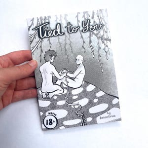 May include: A black and white illustrated book cover titled Tied to You, featuring two elf-like figures connected by a vine. The cover includes an 18+ NSFW label and the text by Insectrun, set against a background of hanging willow branches.