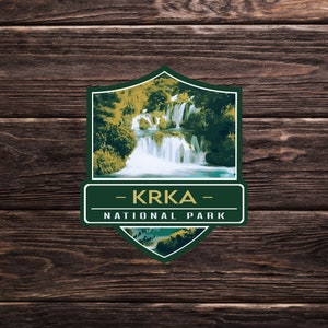 May include: A green and gold illustrated badge with a waterfall scene and the text "KRKA NATIONAL PARK".