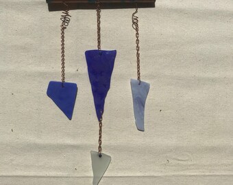 Könnte beinhalten: Ein Kupfer-Windspiel mit drei blauen und weißen Glasstücken, die daran hängen. Die Oberseite des Windspiels hat einen klaren Kristall und blaue Perlen.