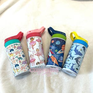 May include: Four stainless steel water bottles with different colourful designs. The designs include dinosaurs, ballerinas, a rocket ship in space, and sharks. Each bottle has a lid with a carrying handle.