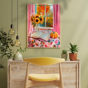 Op de afbeelding: Een schilderij van een knusse herfstsc&egrave;ne met een boek, een kopje thee, een pompoen en zonnebloemen in een vaas op een bloemenkleed. Het raam achter de sc&egrave;ne toont een uitzicht op herfstbladeren.