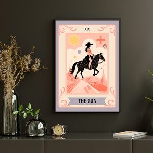 May include: A tarot card illustration depicting The Sun card. The card features a woman riding a horse in a pink and orange landscape. The card is titled "The Sun" and has the Roman numeral XIX in the top left corner.