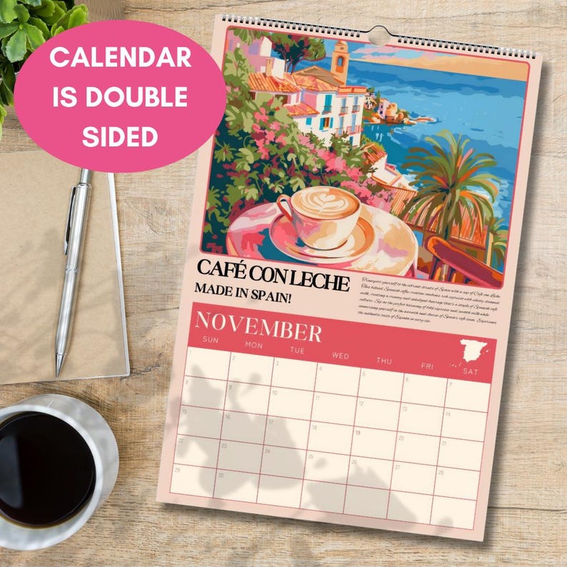 Puede incluir: Calendario de doble cara con una ilustraci&oacute;n de una escena de caf&eacute; espa&ntilde;ol, con el texto "CAF&Eacute; CON LECHE MADE IN SPAIN!" y el mes de noviembre. El calendario tiene una encuadernaci&oacute;n en espiral y un color de acento rosa.