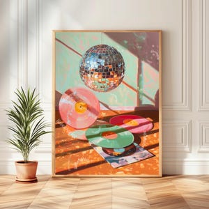May include: A framed art print depicting a disco ball and vinyl records in pink, red, and green. The artwork has a retro feel with a light orange and green background. A potted plant is in the foreground. The image has a warm, inviting atmosphere.