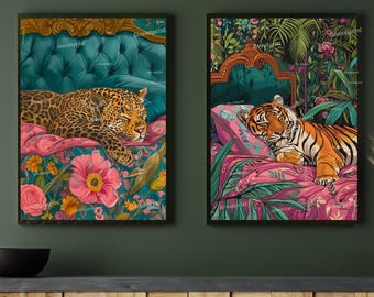 May include: Two framed art prints. One features a leopard resting on a floral bed with a teal headboard. The other print shows a tiger resting on a pink floral bed with a green headboard and tropical foliage.