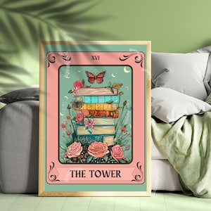 May include: A framed tarot card print featuring a stack of books with flowers and a butterfly. The card has a pink border and a teal background. The text "THE TOWER" is at the bottom, and "XVI" is at the top. The artwork has a vintage aesthetic.
