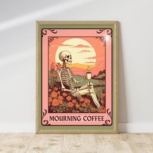 May include: Framed art print featuring a skeleton relaxing in a field of orange roses, holding a coffee cup. The background shows a sunset and mountains. The text "MOURNING COFFEE" is at the bottom of the print. The frame is a light green color.