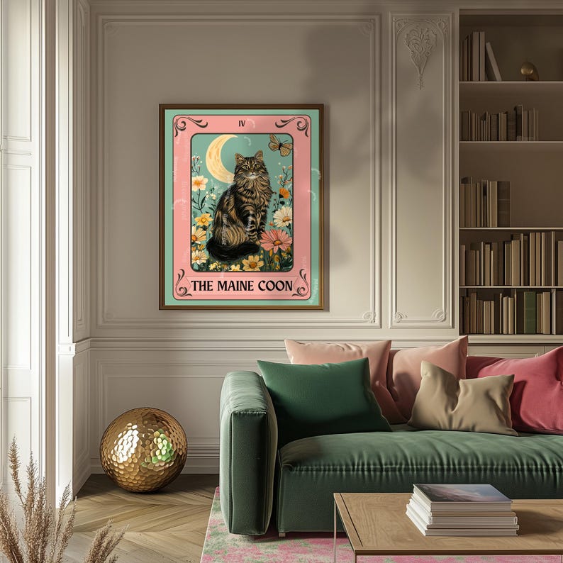 May include: A framed print featuring a Maine Coon cat in a tarot card design. The artwork showcases the cat amidst flowers, a crescent moon, and a butterfly, with the text "THE MAINE COON" at the bottom. The frame is brown, and the background is a mix of pink and teal.