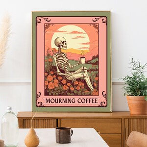May include: A framed art print featuring a skeleton enjoying coffee in a field of roses under a sunset. The artwork has a vintage style with a color palette of pink, orange, and green. The text "MOURNING COFFEE" is displayed at the bottom.