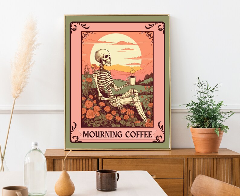 May include: A framed art print featuring a skeleton enjoying coffee in a field of roses under a sunset. The artwork has a vintage style with a color palette of pink, orange, and green. The text "MOURNING COFFEE" is displayed at the bottom.