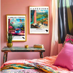 K&ouml;nnte beinhalten: Zwei gerahmte Kunstdrucke mit goldenen Rahmen h&auml;ngen an einer rosa Wand. Ein Druck zeigt "Tarrazu Coffee" und zeigt eine Kaffeetasse mit Schmetterlingen. Der andere zeigt "Caf&eacute;zinho" und zeigt eine Kaffeetasse mit Landschaftsansicht.