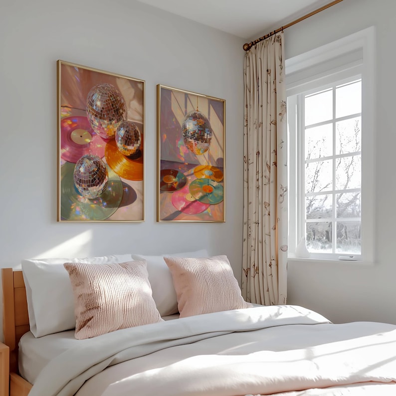 K&ouml;nnte beinhalten: Zwei gerahmte Kunstdrucke mit Discokugeln und Schallplatten in Rosa-, Orange- und Gr&uuml;nt&ouml;nen. Das Kunstwerk wird &uuml;ber einem Bett mit rosa Kissen und wei&szlig;er Bettw&auml;sche ausgestellt. Der Raum hat ein Fenster mit gemusterten Vorh&auml;ngen.