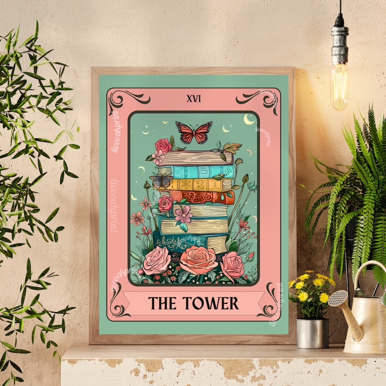 May include: A framed tarot card print featuring a stack of books adorned with flowers and butterflies. The card reads "THE TOWER" at the bottom, with "XVI" at the top. The color palette includes pink, teal, and various book colors.