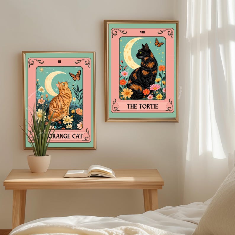 May include: Two framed art prints featuring cat illustrations in a tarot card style. One shows an orange tabby cat, the other a black and orange cat. Both have a crescent moon, flowers, and butterflies.