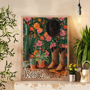 May include: A framed print of a floral wallpaper design with a cowboy hat and boots. The wallpaper features a dark green background with pink, orange, and yellow flowers. The boots are brown leather with pink stitching and the hat is black.