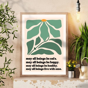 May include: A framed print with a green and orange abstract floral design. The print features the text "may all beings be safe. may all beings be happy. may all beings be healthy. may all beings live with ease."
