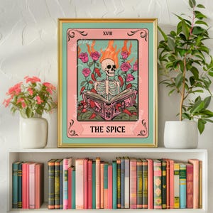 Puede incluir: Una carta de tarot rosa y verde con un esqueleto sosteniendo un libro. La carta se titula "The Spice" y tiene el número XVIII. El esqueleto está rodeado de chiles rojos y rosas rosas.