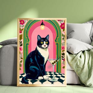 May include: A framed art print featuring a tuxedo cat with yellow eyes, sitting next to a martini glass with olives. The background includes a pink archway, floral accents, and a black and white checkered floor.