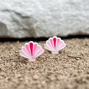 May include: A pair of silver stud earrings with pink and red enamel seashell designs.