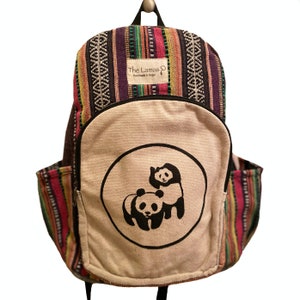 May include: A multi-colored striped backpack with a large white canvas front pocket featuring a black and white panda bear design. The text "The Lamas Handmade in Nepal" is printed on a small tag attached to the backpack.