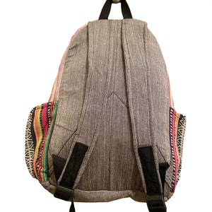 May include: A gray backpack with black straps and colorful woven trim. The backpack has a zippered closure and a large main compartment.