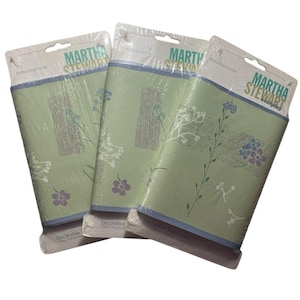 Peut inclure: Trois chemins de table décoratifs Martha Stewart emballés. Les chemins de table ont un fond vert clair avec des motifs floraux et de vigne blancs, bleus et violets. L'emballage porte le logo Martha Stewart.