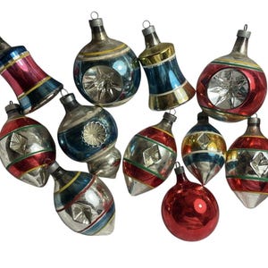May include: A collection of vintage Christmas ornaments in various shapes and colors. The ornaments feature silver, red, blue, and gold accents, with star-shaped cutouts and striped designs. These festive decorations are perfect for holiday decor.