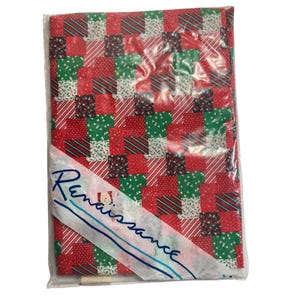 May include: A package of Christmas-themed wrapping paper. The paper features a patchwork design with red, green, and white squares. Some squares have stripes, dots, or Christmas tree patterns. The package is sealed in clear plastic with a white label that reads "Renaissance".